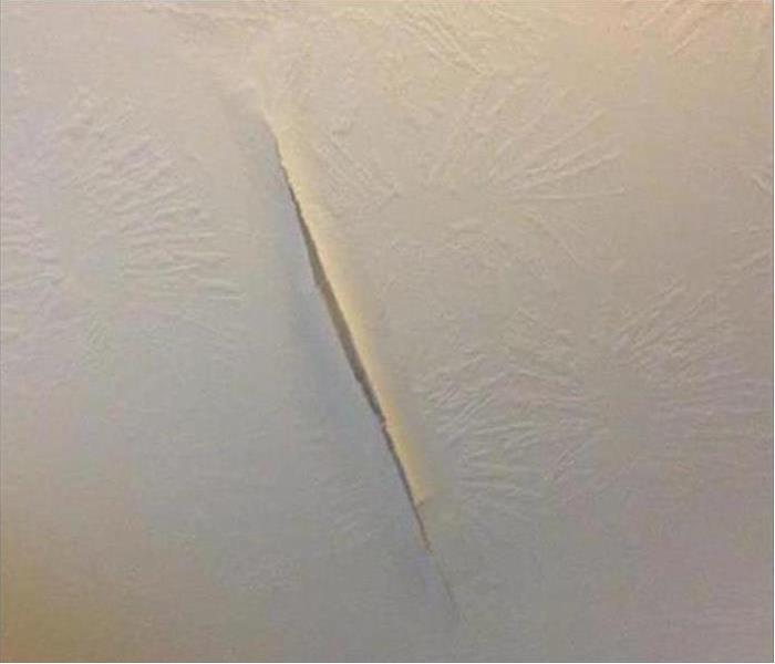 Wet ceiling of condo with drywall peeling off