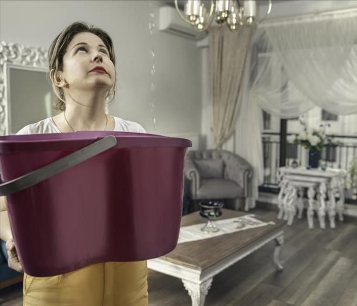 woman standing with bucket catching water